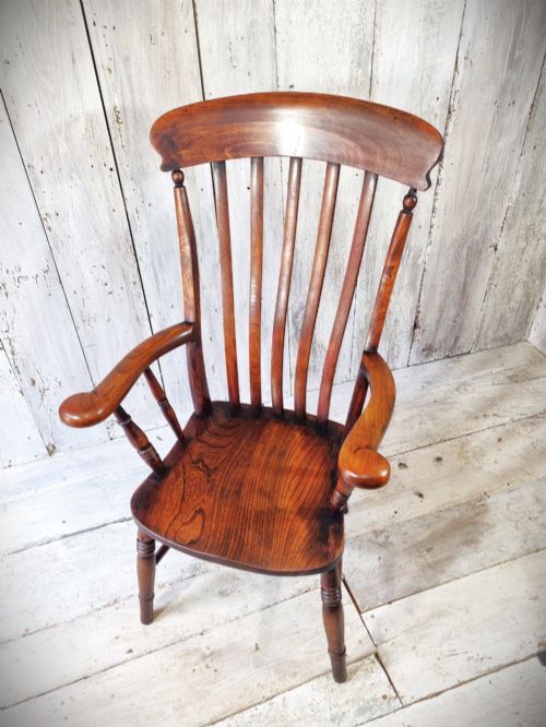 fig 1. A Victorian lath back Windsor armchair crafted from warm brown polished wood with a shaped elm seat and turned beech legs.