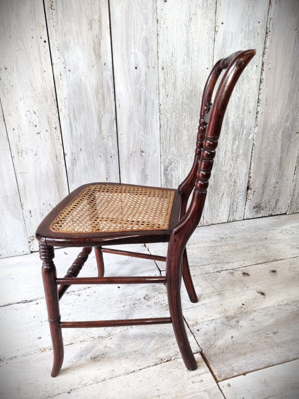 A Regency period side chair featuring a simulated rosewood finish, a rope-twist top rail, a brass-mounted centre splat, turned legs, and a hand-woven cane seat. View IV