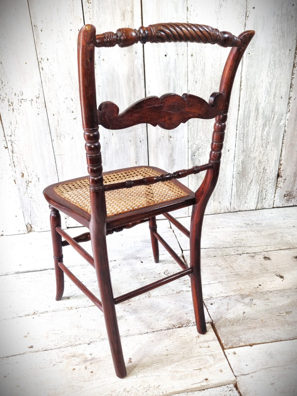 A Regency period side chair featuring a simulated rosewood finish, a rope-twist top rail, a brass-mounted centre splat, turned legs, and a hand-woven cane seat. View V