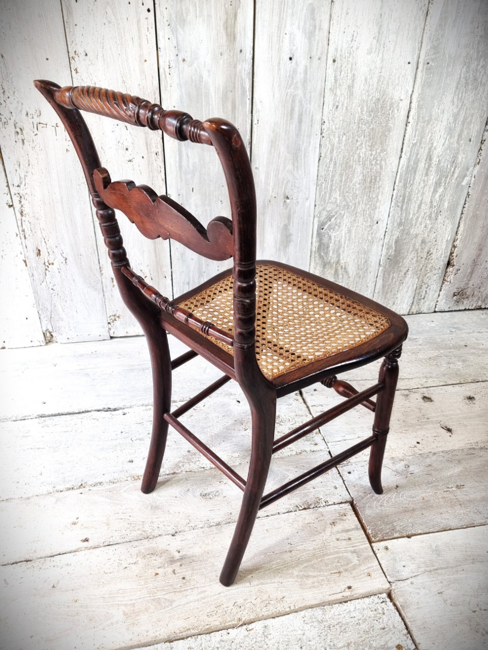 A Regency period side chair featuring a simulated rosewood finish, a rope-twist top rail, a brass-mounted centre splat, turned legs, and a hand-woven cane seat. View VI