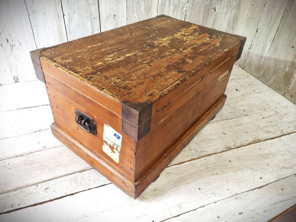 A late Victorian pine travel trunk featuring a distressed wood lid, painted sides with vintage shipping labels, central keyhole, and metal corner reinforcements. View II