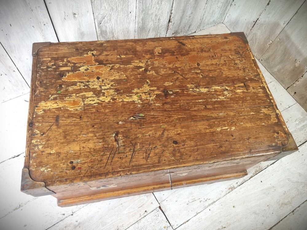 A late Victorian pine travel trunk featuring a distressed wood lid, painted sides with vintage shipping labels, central keyhole, and metal corner reinforcements. View IV