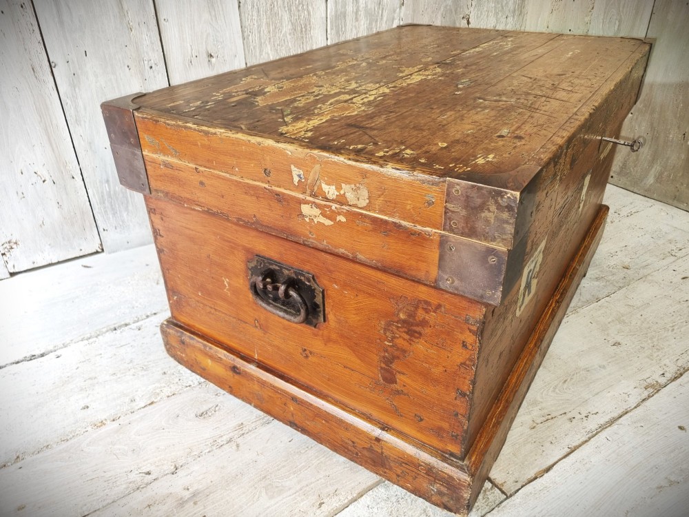A late Victorian pine travel trunk featuring a distressed wood lid, painted sides with vintage shipping labels, central keyhole, and metal corner reinforcements. View X