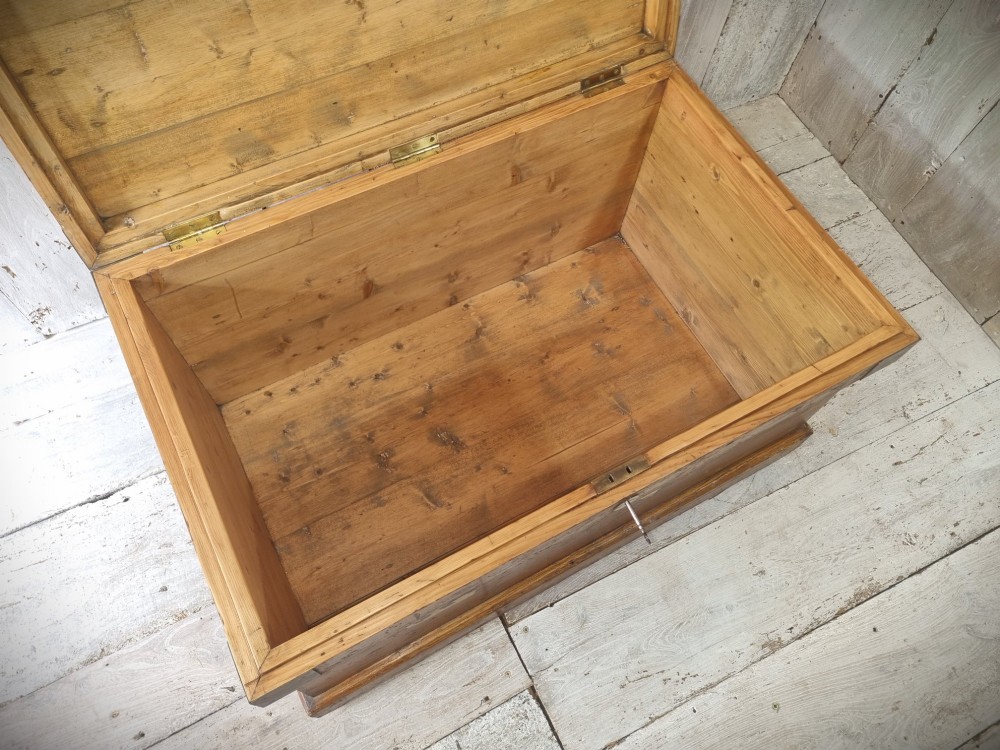 A late Victorian pine travel trunk featuring a distressed wood lid, painted sides with vintage shipping labels, central keyhole, and metal corner reinforcements. View XIII