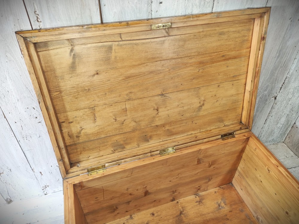 A late Victorian pine travel trunk featuring a distressed wood lid, painted sides with vintage shipping labels, central keyhole, and metal corner reinforcements. View XIV