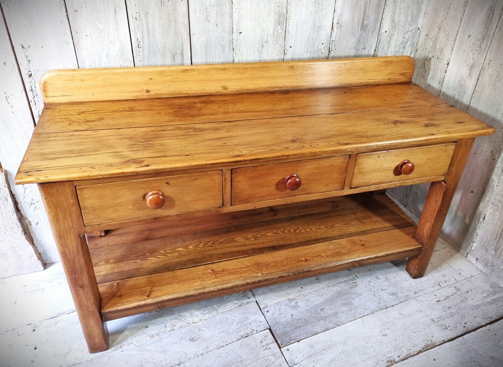A Victorian pine dresser base featuring three upper drawers with turned wooden knobs, a simple rear upstand, and an open lower pot shelf. View II