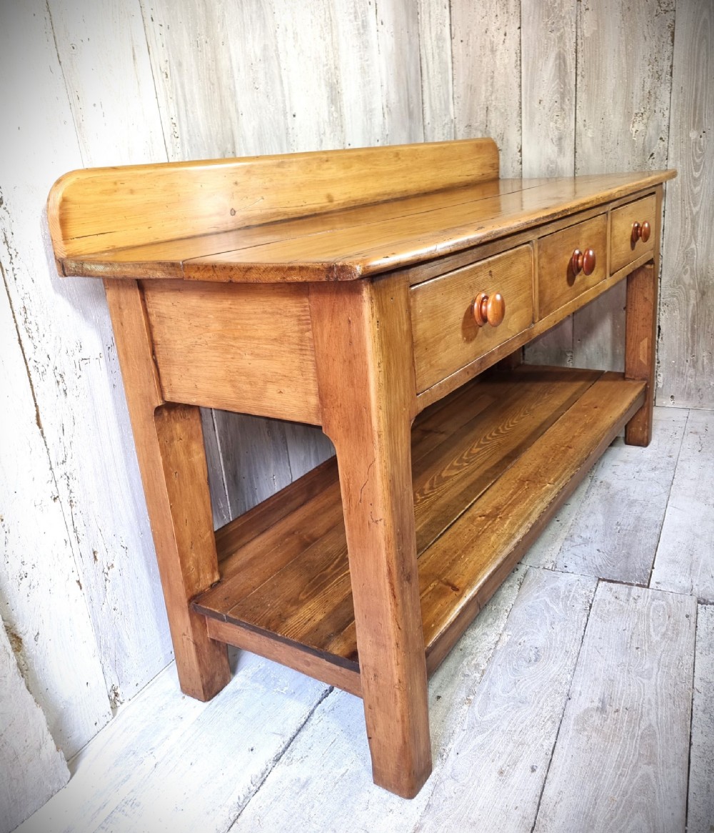 A Victorian pine dresser base featuring three upper drawers with turned wooden knobs, a simple rear upstand, and an open lower pot shelf. View IV