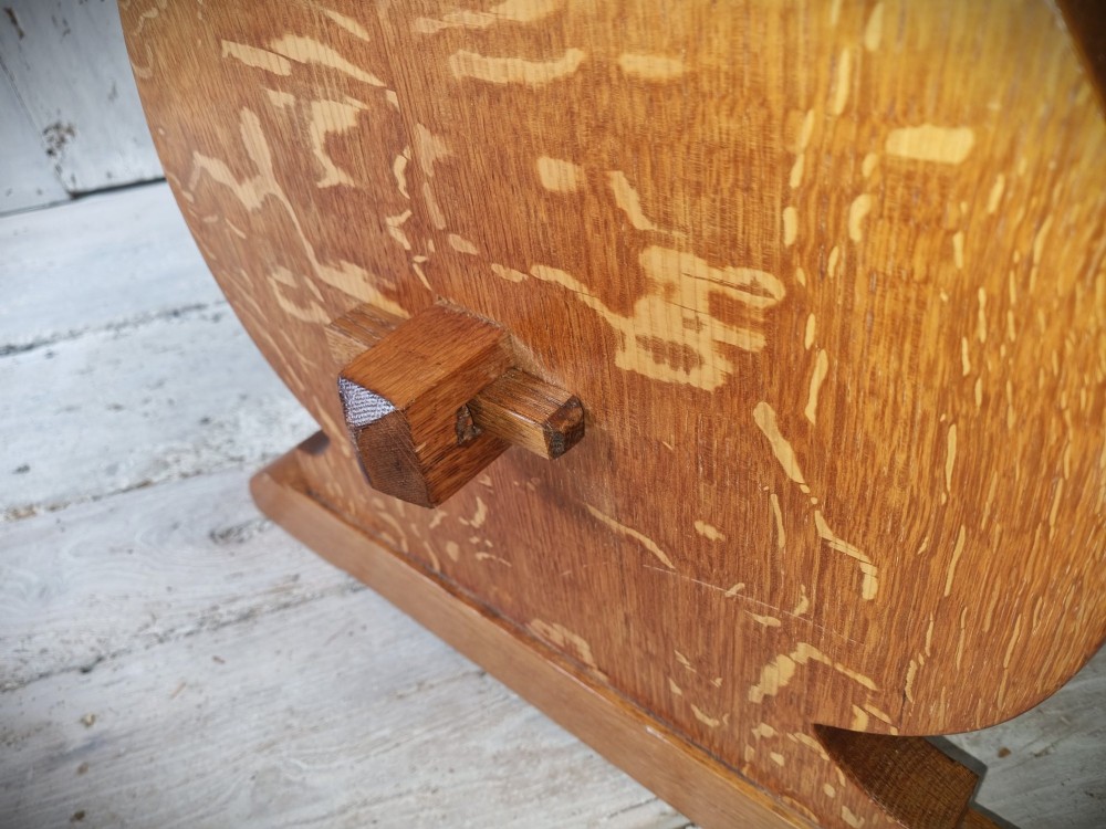 A solid golden oak trestle table featuring a rectangular top, shaped side supports with visible medullary ray grain patterns, and a central stretcher secured with pegged tenons. View VII