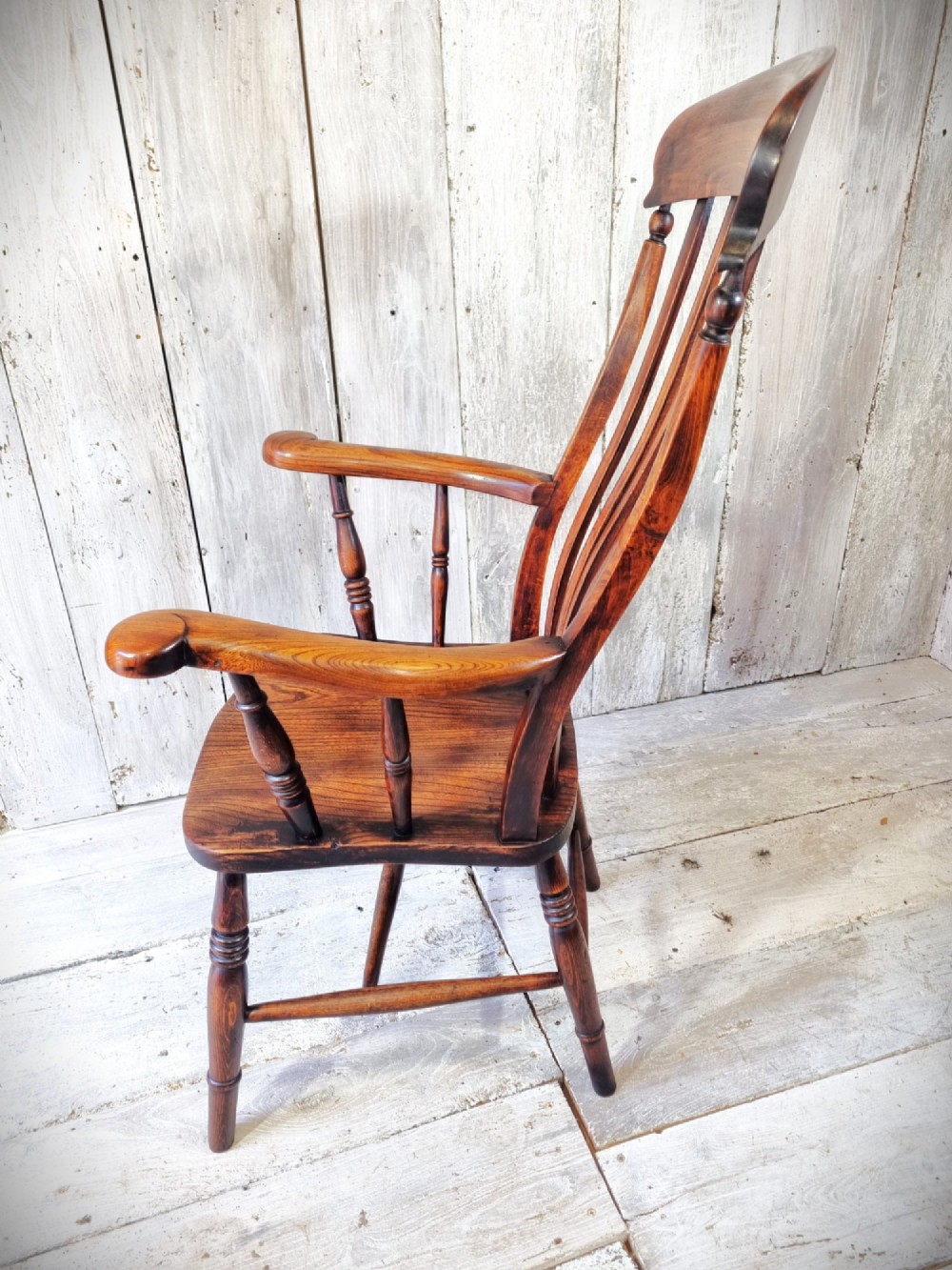 A Victorian lath back Windsor armchair crafted from warm brown polished wood with a shaped elm seat and turned beech legs. View III