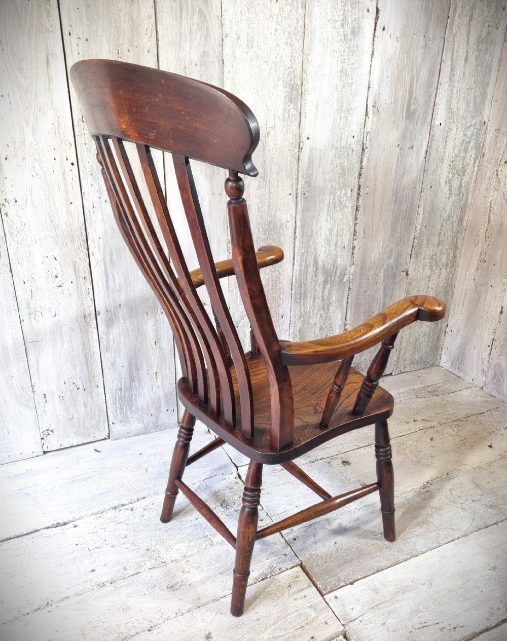 A Victorian lath back Windsor armchair crafted from warm brown polished wood with a shaped elm seat and turned beech legs. View V