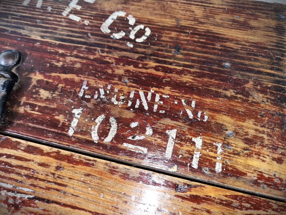 A rectangular warm brown wooden tool box featuring white stencilled text, a central winged logo, and an iron top clasp. View VII
