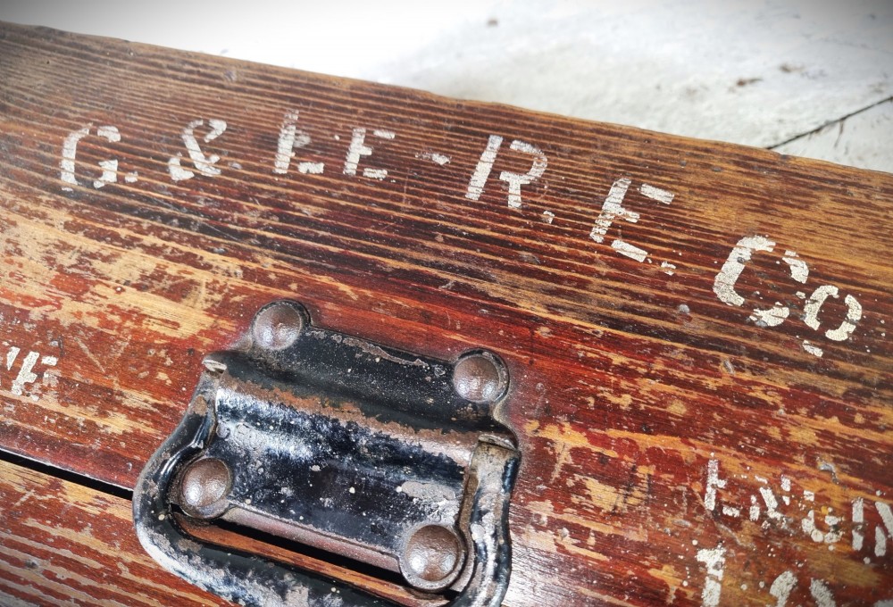 A rectangular warm brown wooden tool box featuring white stencilled text, a central winged logo, and an iron top clasp. View VIII