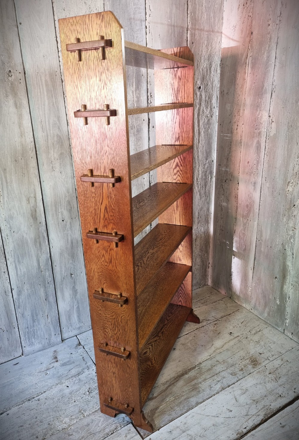 A tall open-backed oak shelving unit featuring seven horizontal tiers and visible side pegged joinery. View II