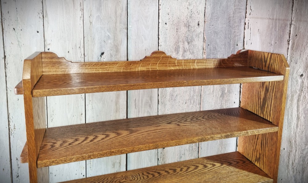 A tall open-backed oak shelving unit featuring seven horizontal tiers and visible side pegged joinery. View V
