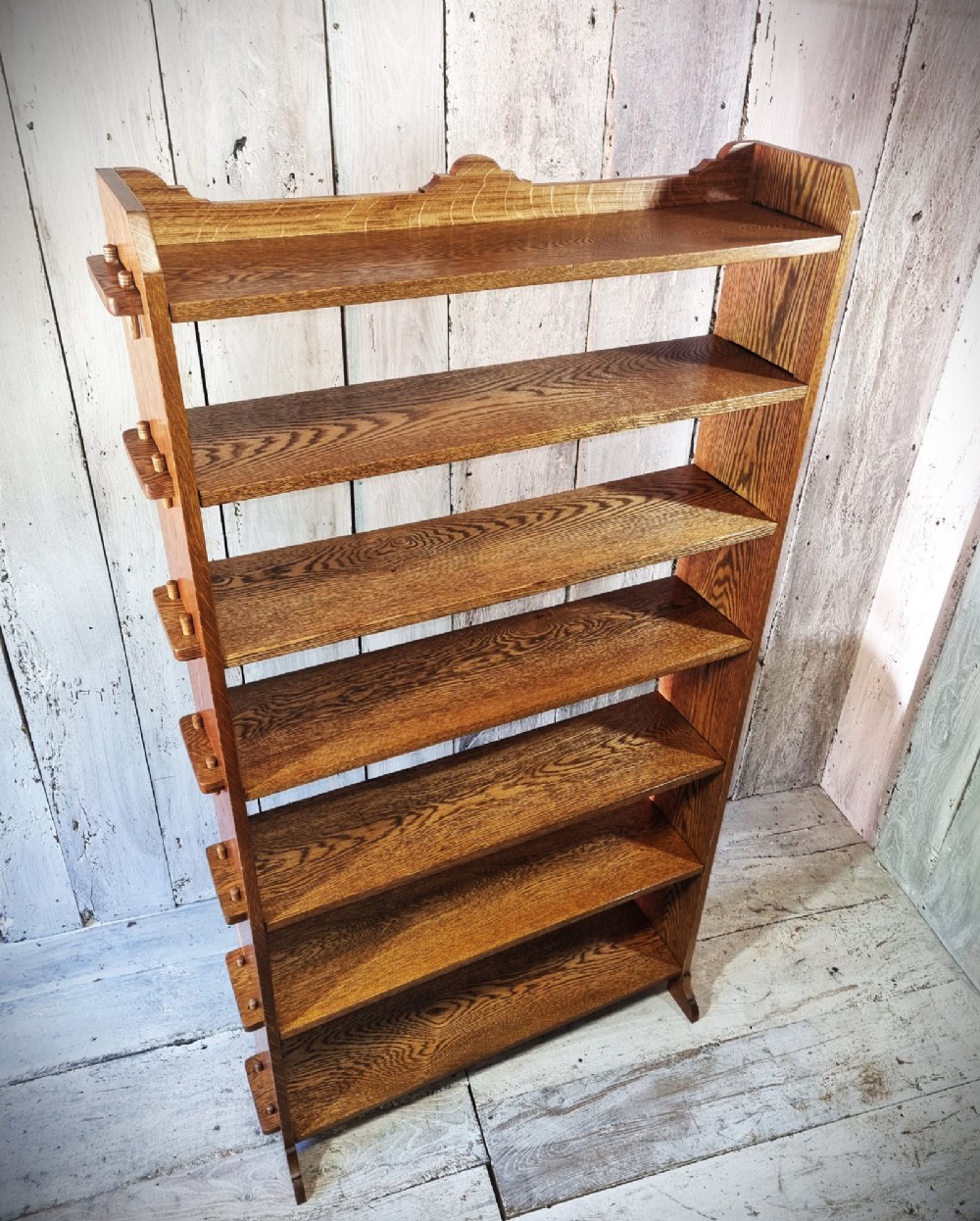 A tall open-backed oak shelving unit featuring seven horizontal tiers and visible side pegged joinery. View VI