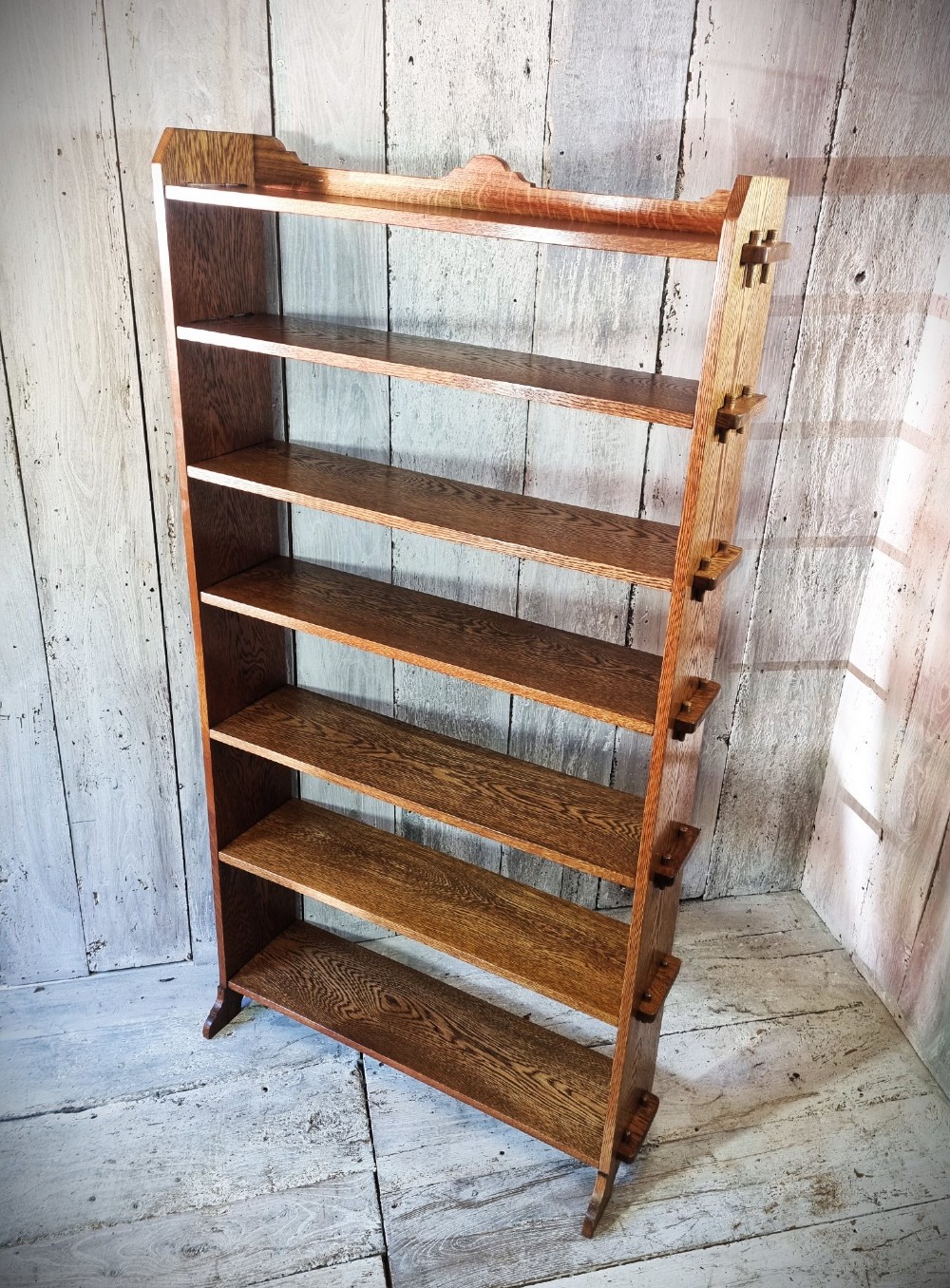 A tall open-backed oak shelving unit featuring seven horizontal tiers and visible side pegged joinery. View XI