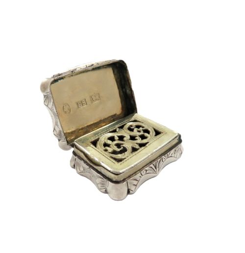 fig 1. A small rectangular Victorian sterling silver vinaigrette box featuring intricate foliate engraving and a serpentine outline.
