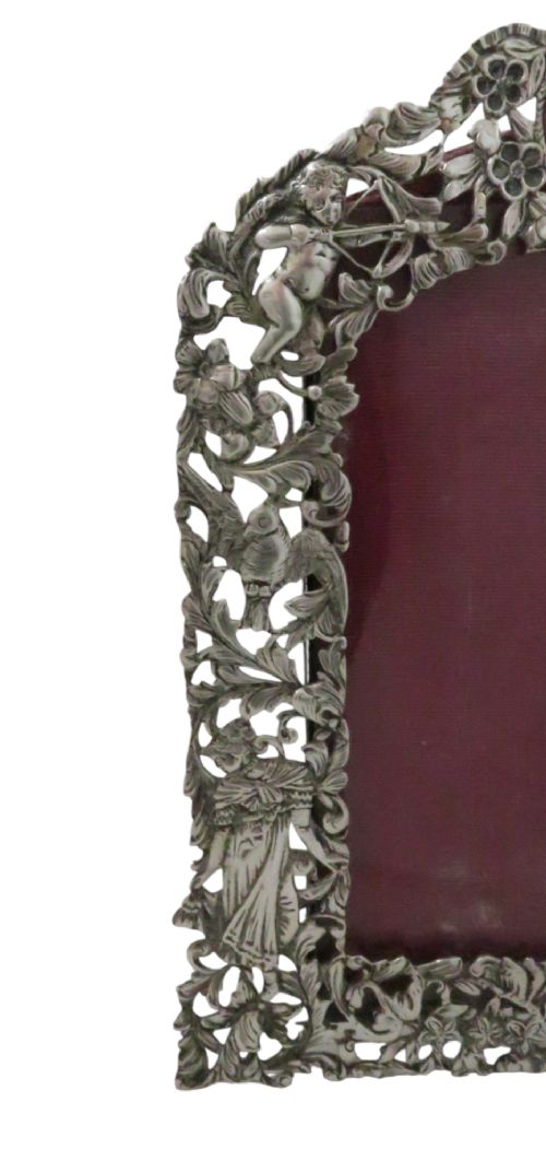 An ornate late Victorian sterling silver easel-back photo frame decorated with pierced cherubs, birds, and floral scrollwork, fitted with a burgundy velvet backing. View VII