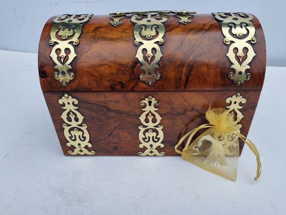 A Victorian walnut dome top stationery box featuring decorative pierced brass strapwork mounts and keyhole escutcheon.