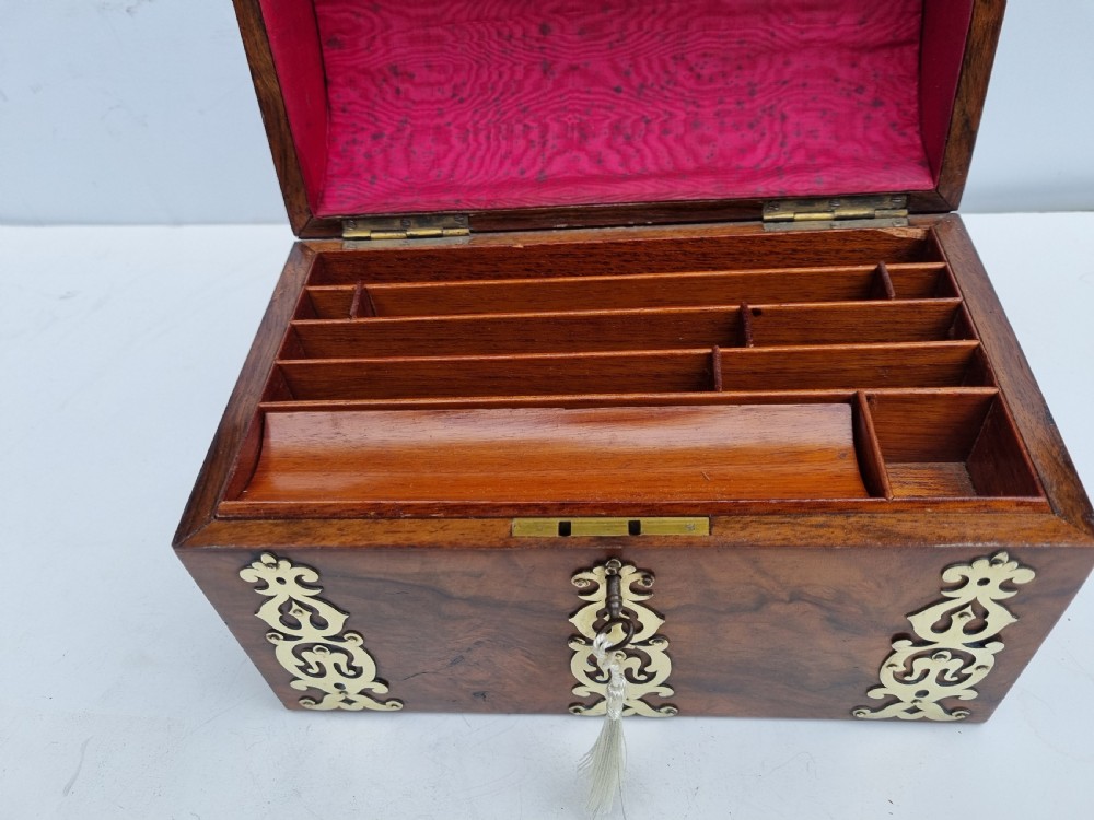 A Victorian walnut dome top stationery box featuring decorative pierced brass strapwork mounts and keyhole escutcheon. View IV