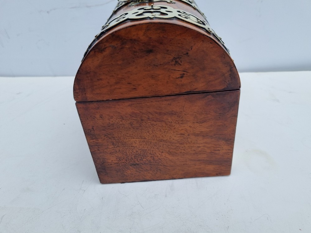 A Victorian walnut dome top stationery box featuring decorative pierced brass strapwork mounts and keyhole escutcheon. View VI