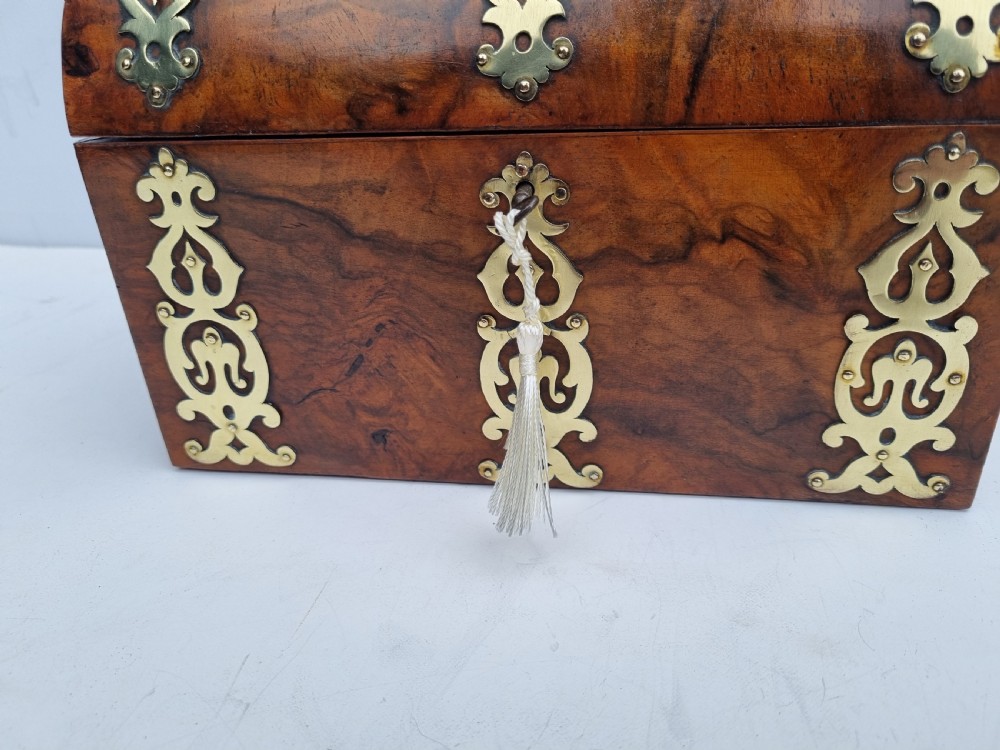 A Victorian walnut dome top stationery box featuring decorative pierced brass strapwork mounts and keyhole escutcheon. View IX