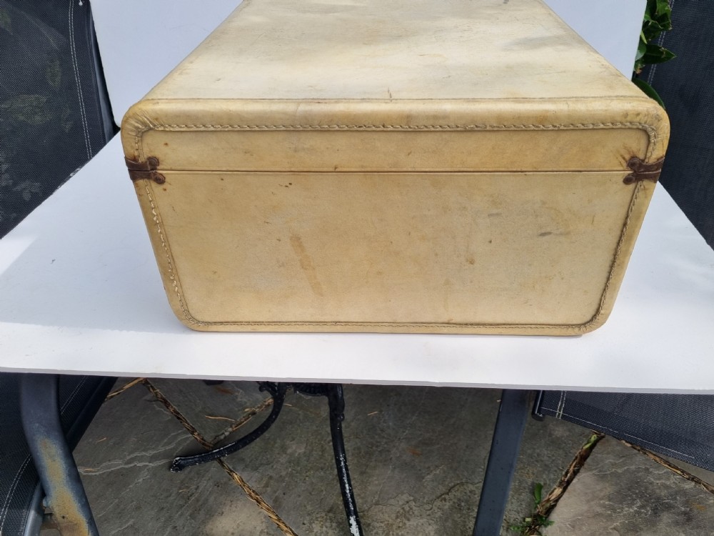 An antique cream vellum leather weekend case with twin brass latches and a central stitched leather handle. View II