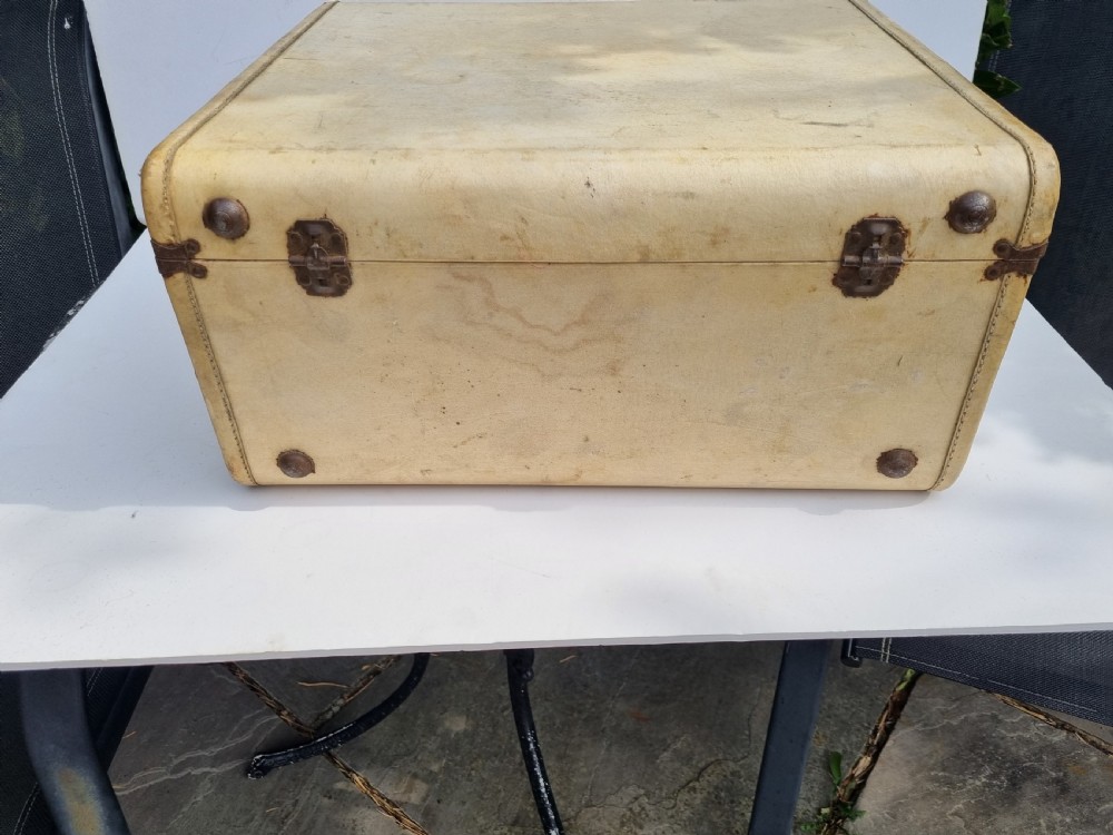 An antique cream vellum leather weekend case with twin brass latches and a central stitched leather handle. View III