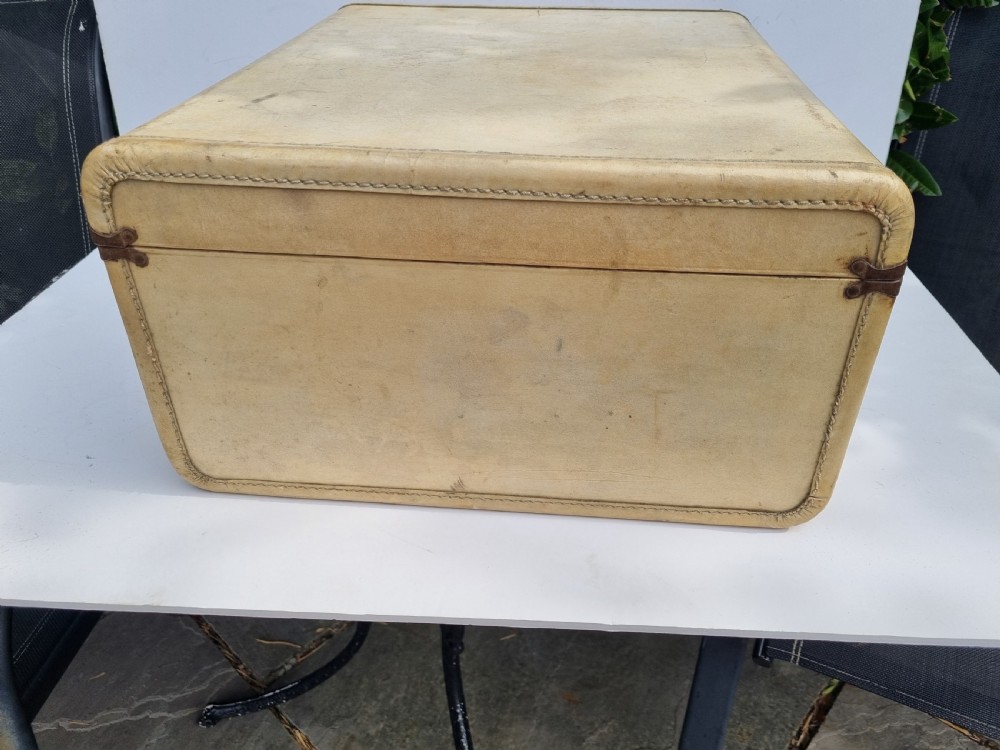 An antique cream vellum leather weekend case with twin brass latches and a central stitched leather handle. View IV