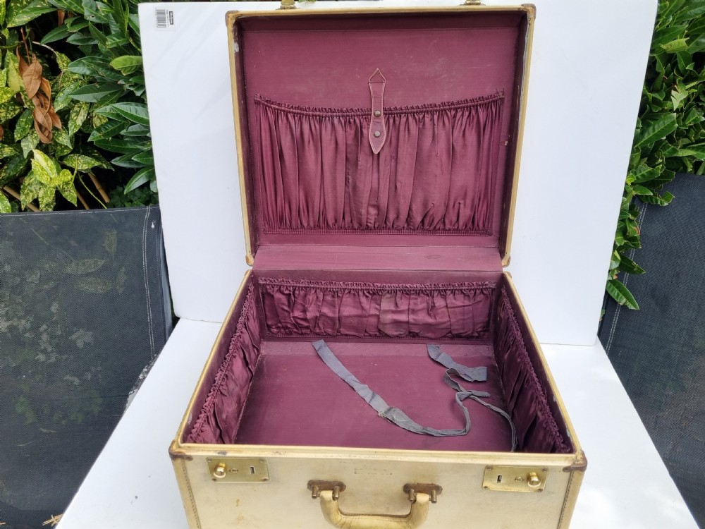 An antique cream vellum leather weekend case with twin brass latches and a central stitched leather handle. View V
