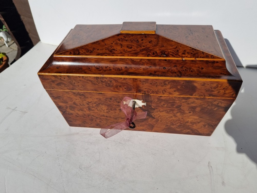 A Georgian burr yew tea caddy featuring a sarcophagus-shaped lid, boxwood stringing inlay, and a central keyhole escutcheon. View X