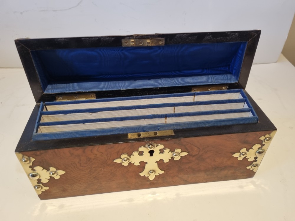 A Victorian burr walnut stationery box with a dome lid, ornamented with pierced brass mounts and a decorative brass keyhole escutcheon. View V