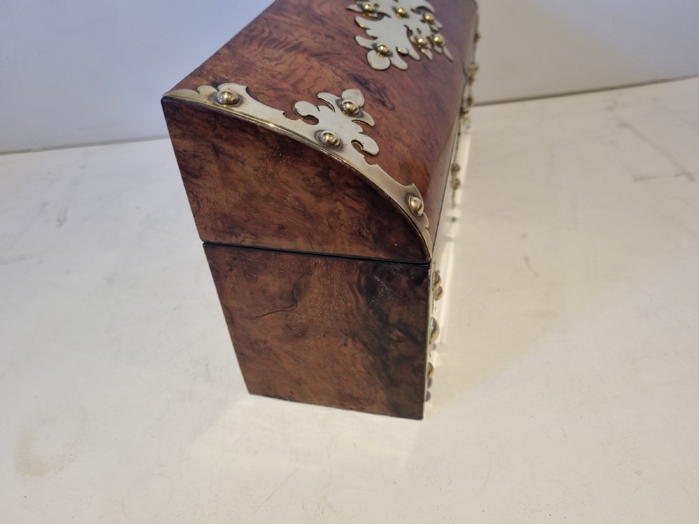 A Victorian burr walnut stationery box with a dome lid, ornamented with pierced brass mounts and a decorative brass keyhole escutcheon. View VI