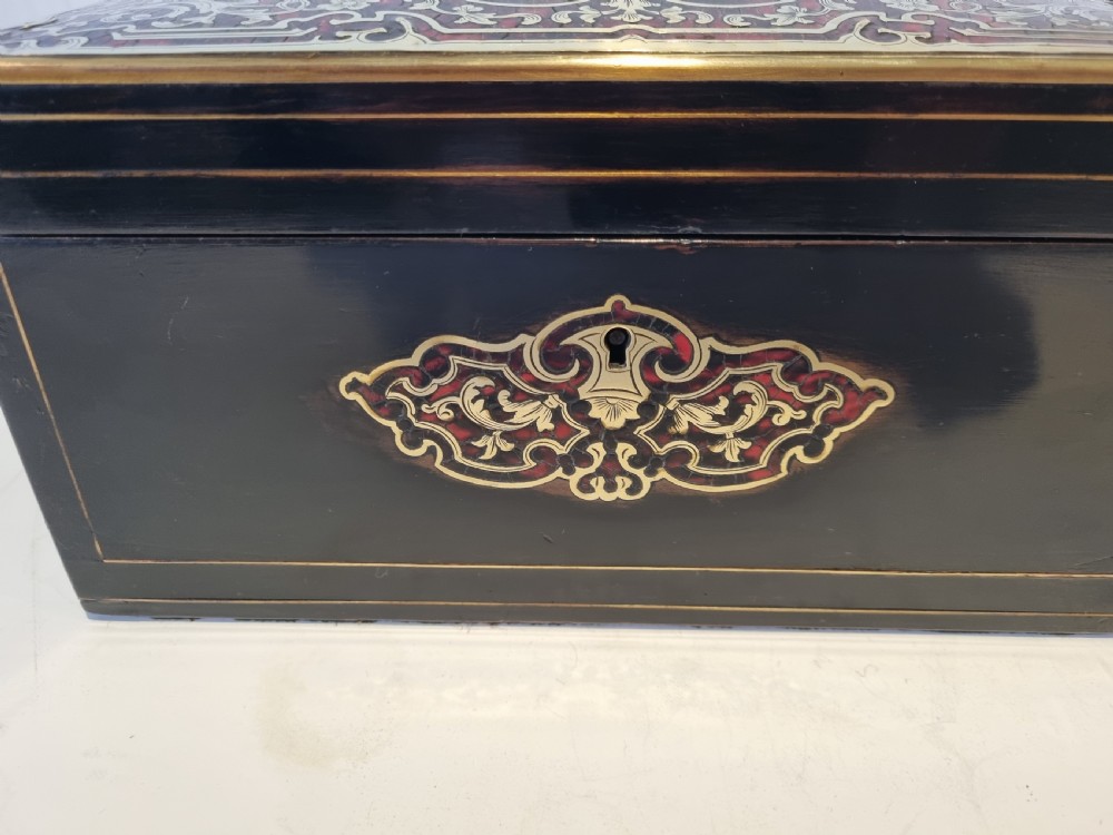 A rectangular ebonised wood tea caddy featuring a lid ornamented with red tortoiseshell and brass Boulle marquetry and a brass-inlaid keyhole escutcheon on the front. View III