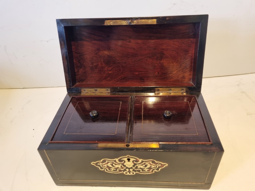 A rectangular ebonised wood tea caddy featuring a lid ornamented with red tortoiseshell and brass Boulle marquetry and a brass-inlaid keyhole escutcheon on the front. View V