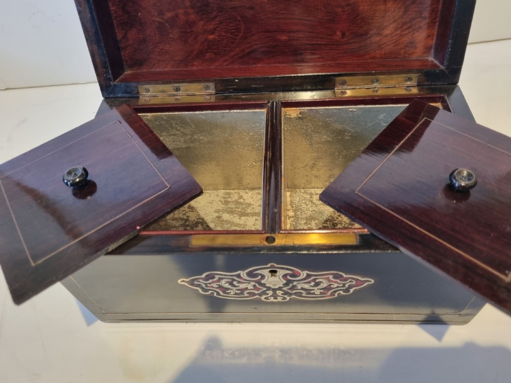 A rectangular ebonised wood tea caddy featuring a lid ornamented with red tortoiseshell and brass Boulle marquetry and a brass-inlaid keyhole escutcheon on the front. View VI