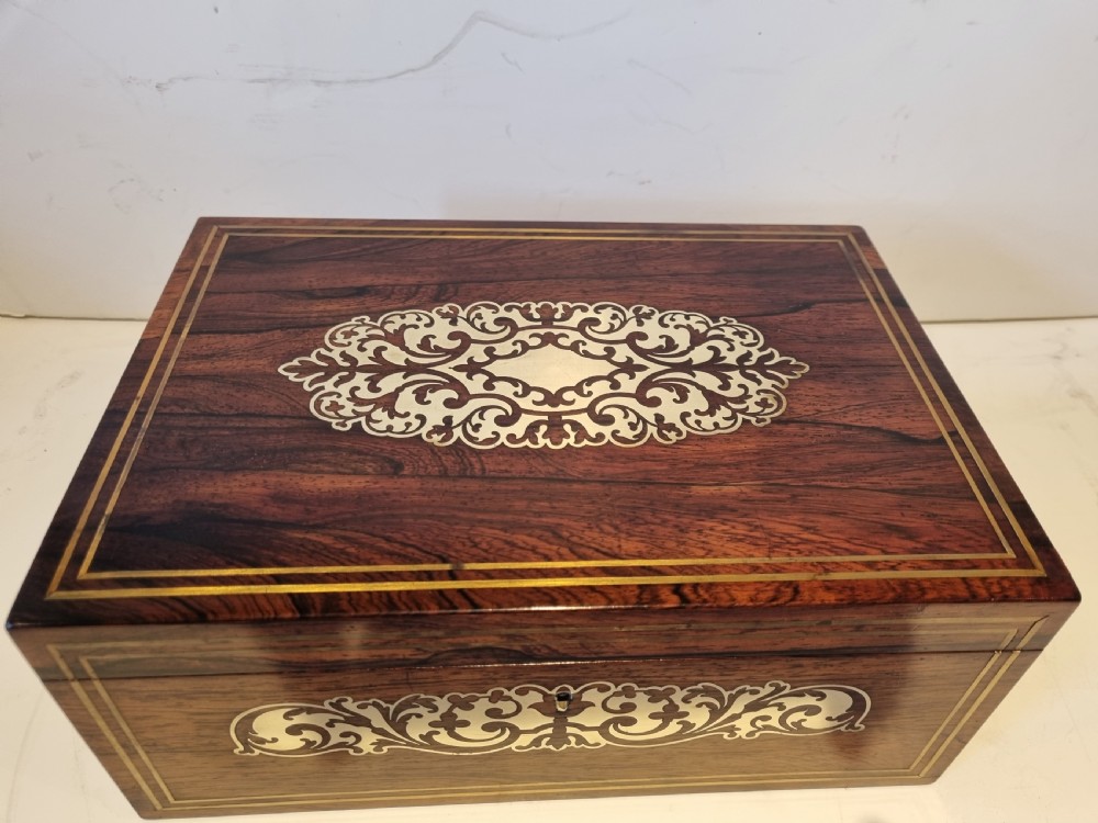A rectangular dark rosewood box featuring intricate brass floral scrollwork inlay and brass double-stringing on the lid and front panel. View II