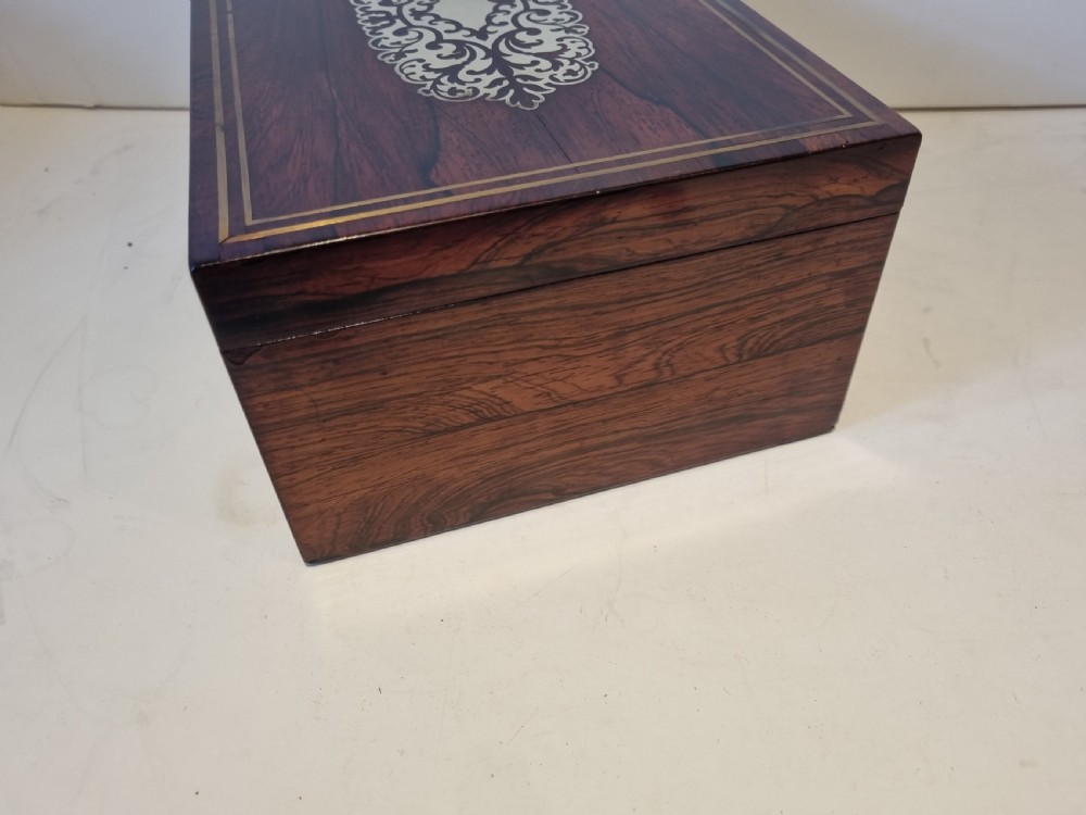 A rectangular dark rosewood box featuring intricate brass floral scrollwork inlay and brass double-stringing on the lid and front panel. View III