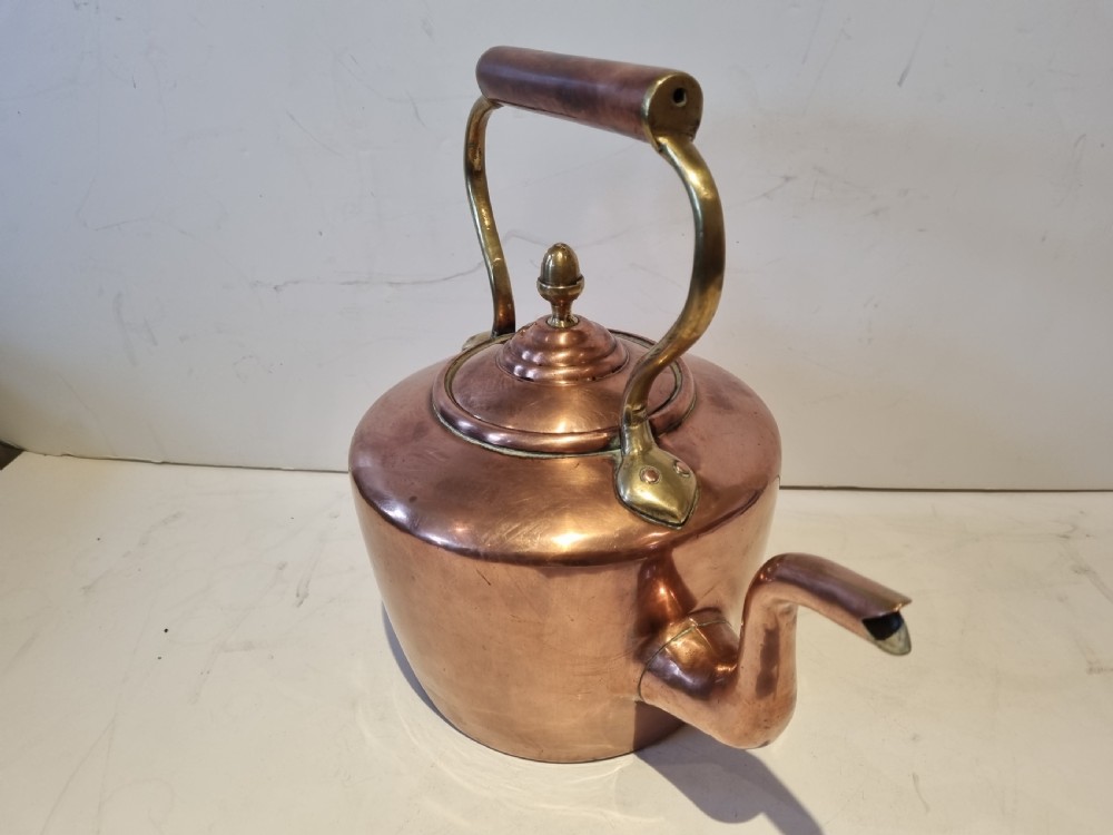 An antique Georgian copper tea kettle featuring a polished body, curved gooseneck spout, domed lid with an acorn finial, and an overhead brass handle. View II