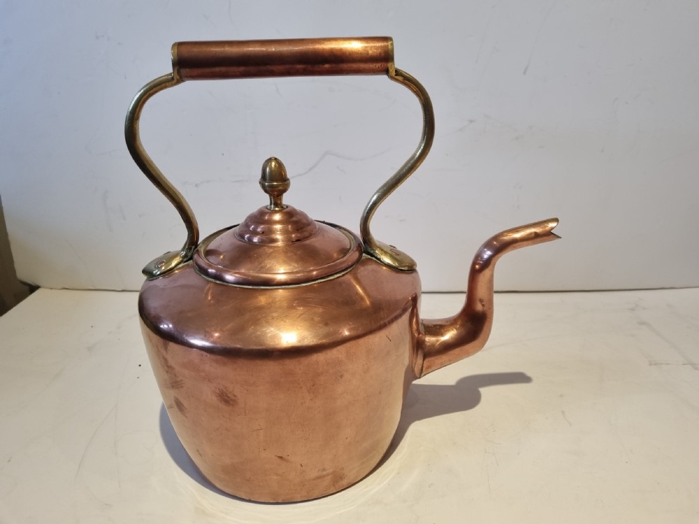 An antique Georgian copper tea kettle featuring a polished body, curved gooseneck spout, domed lid with an acorn finial, and an overhead brass handle. View VIII
