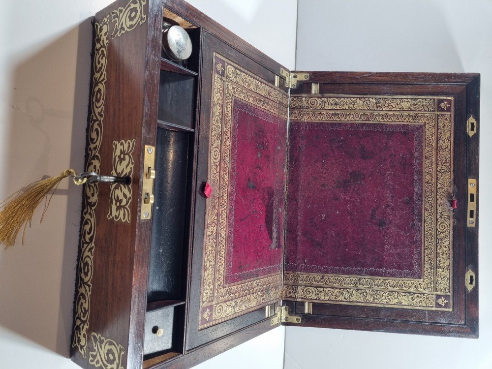 A rectangular dark rosewood writing box featuring intricate brass floral scrollwork inlay around the borders and escutcheon, complete with a key and tassel. View VII
