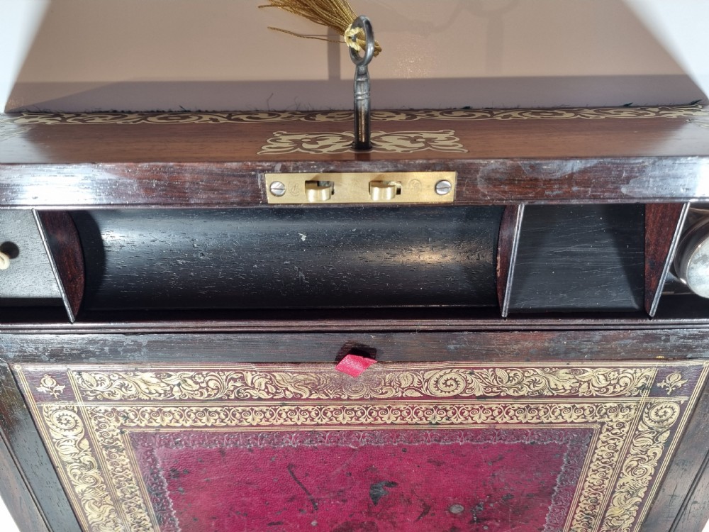 A rectangular dark rosewood writing box featuring intricate brass floral scrollwork inlay around the borders and escutcheon, complete with a key and tassel. View VIII