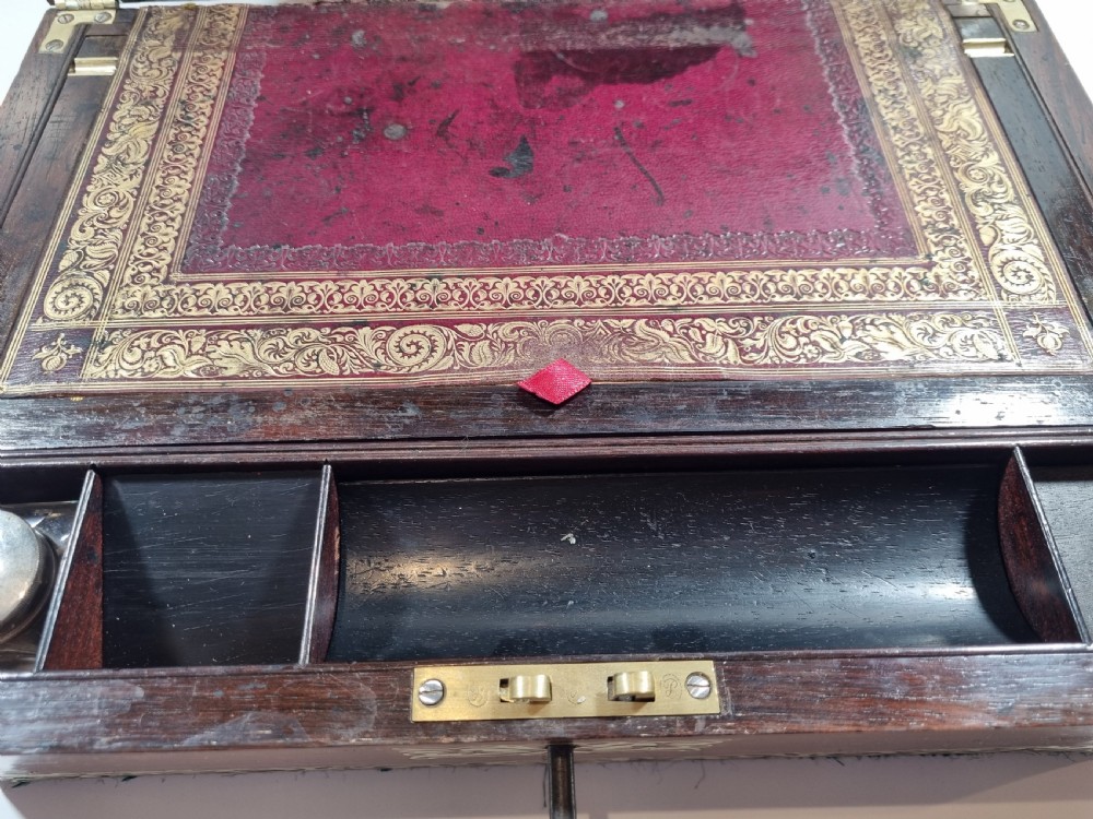 A rectangular dark rosewood writing box featuring intricate brass floral scrollwork inlay around the borders and escutcheon, complete with a key and tassel. View XI