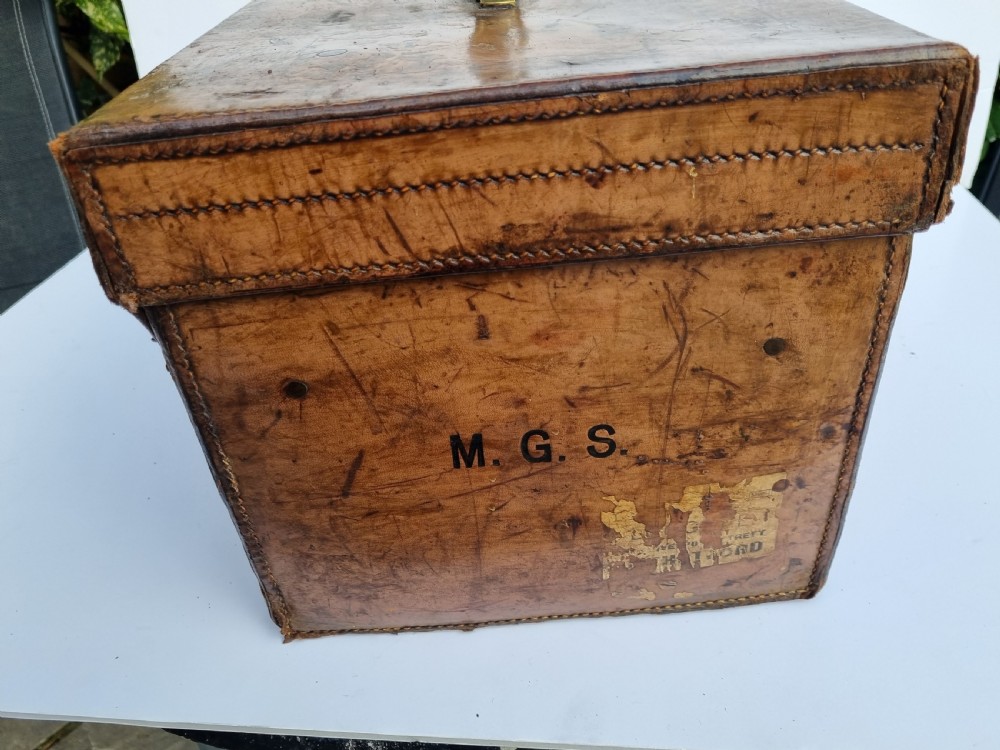 A Victorian tan leather travel trunk featuring hand-stitched edges, brass lever locks, a top carrying handle, and patinated surface wear. View VII