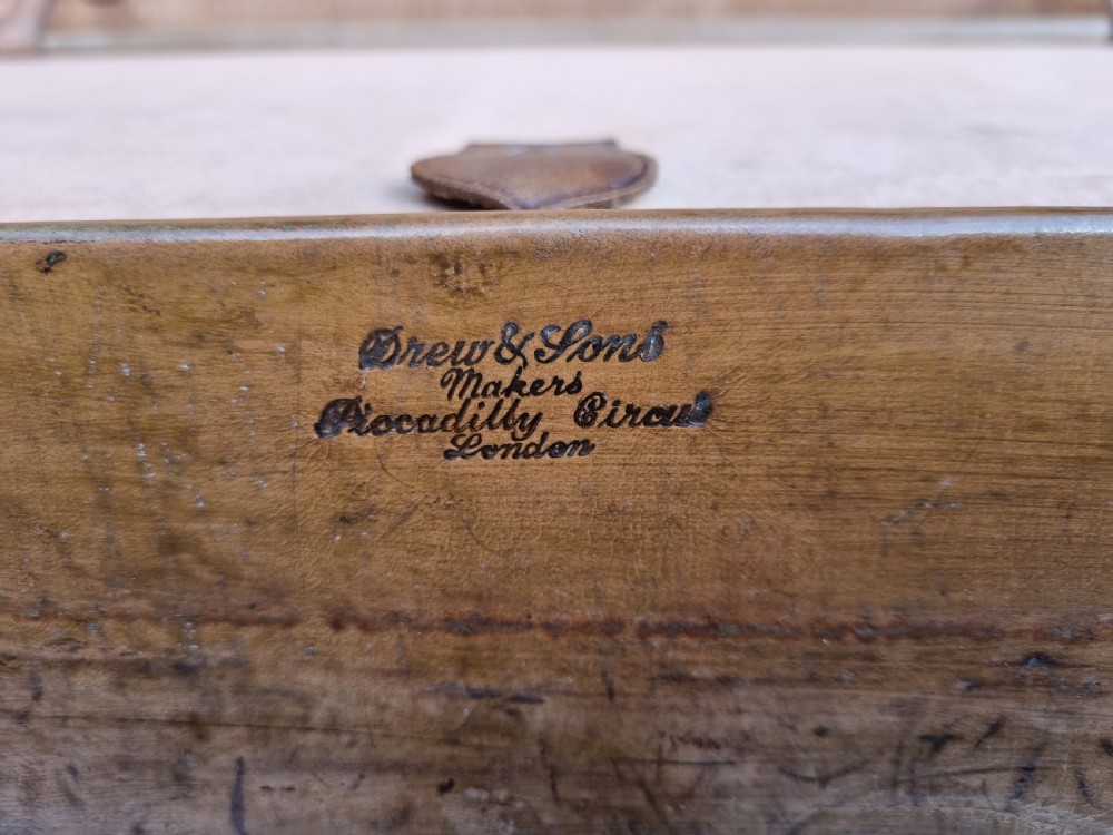 A Victorian tan leather travel trunk featuring hand-stitched edges, brass lever locks, a top carrying handle, and patinated surface wear. View XI