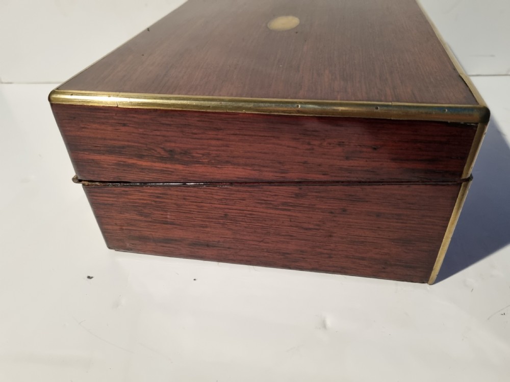 A rectangular dark rosewood document box featuring brass edge binding, an oval brass keyhole escutcheon, and an oval brass top inlay. View VI