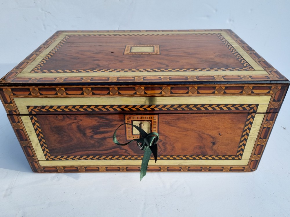 A rectangular Victorian walnut writing box with intricate geometric parquetry inlay borders and a central brass keyhole.