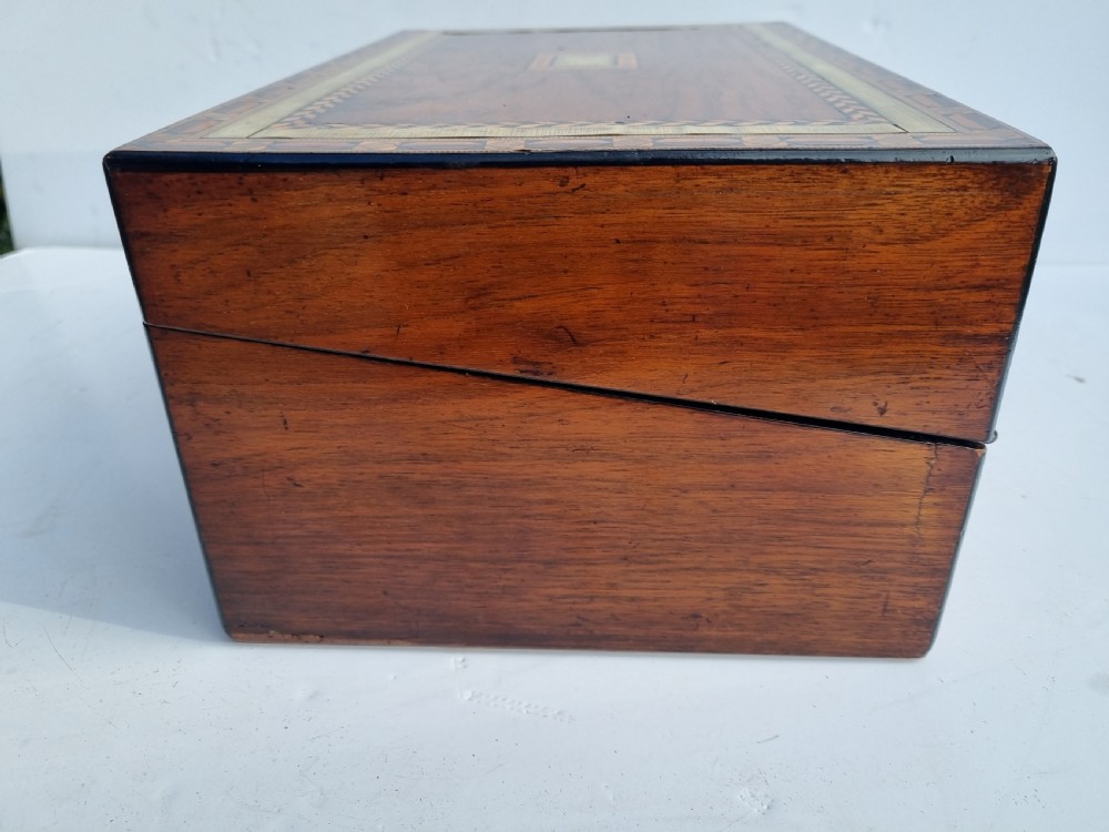 A rectangular Victorian walnut writing box with intricate geometric parquetry inlay borders and a central brass keyhole. View V