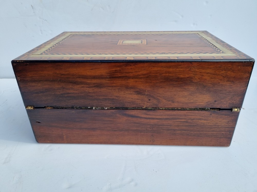 A rectangular Victorian walnut writing box with intricate geometric parquetry inlay borders and a central brass keyhole. View VI