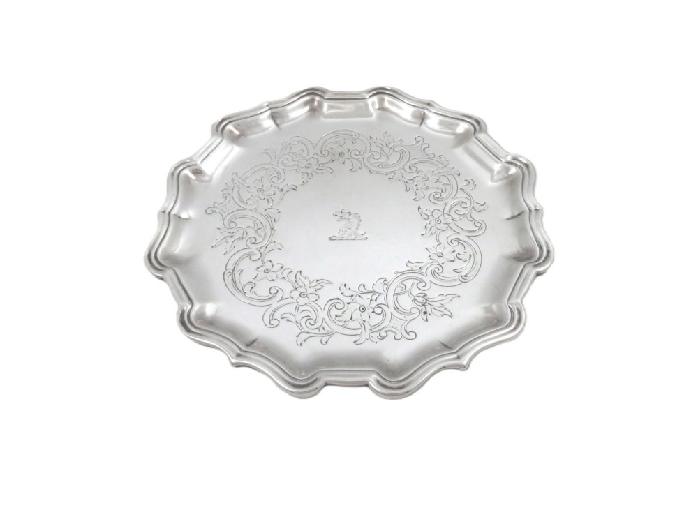 A circular 18th-century sterling silver card tray with a shaped piecrust rim, detailed scroll engraving, and a central heraldic crest. View III